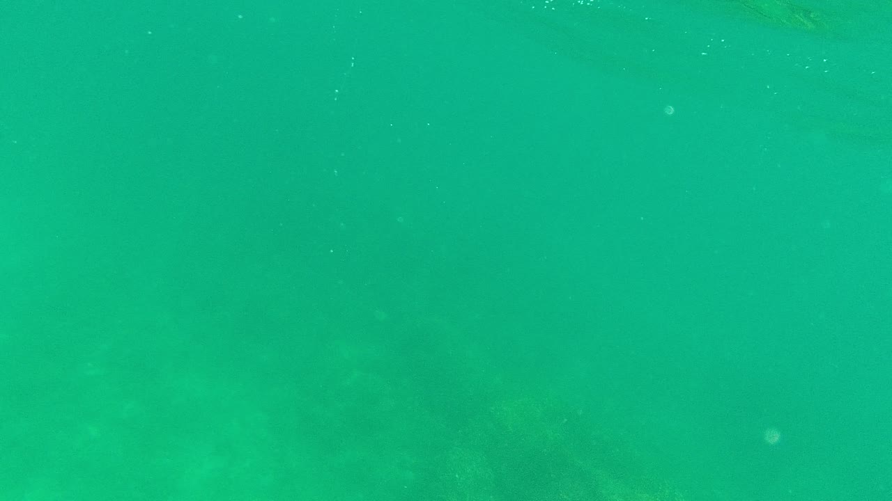 Submerged turquoise water in Palmilla Los Cabos with a faint rocky seabed visible through the haze and no visible people.