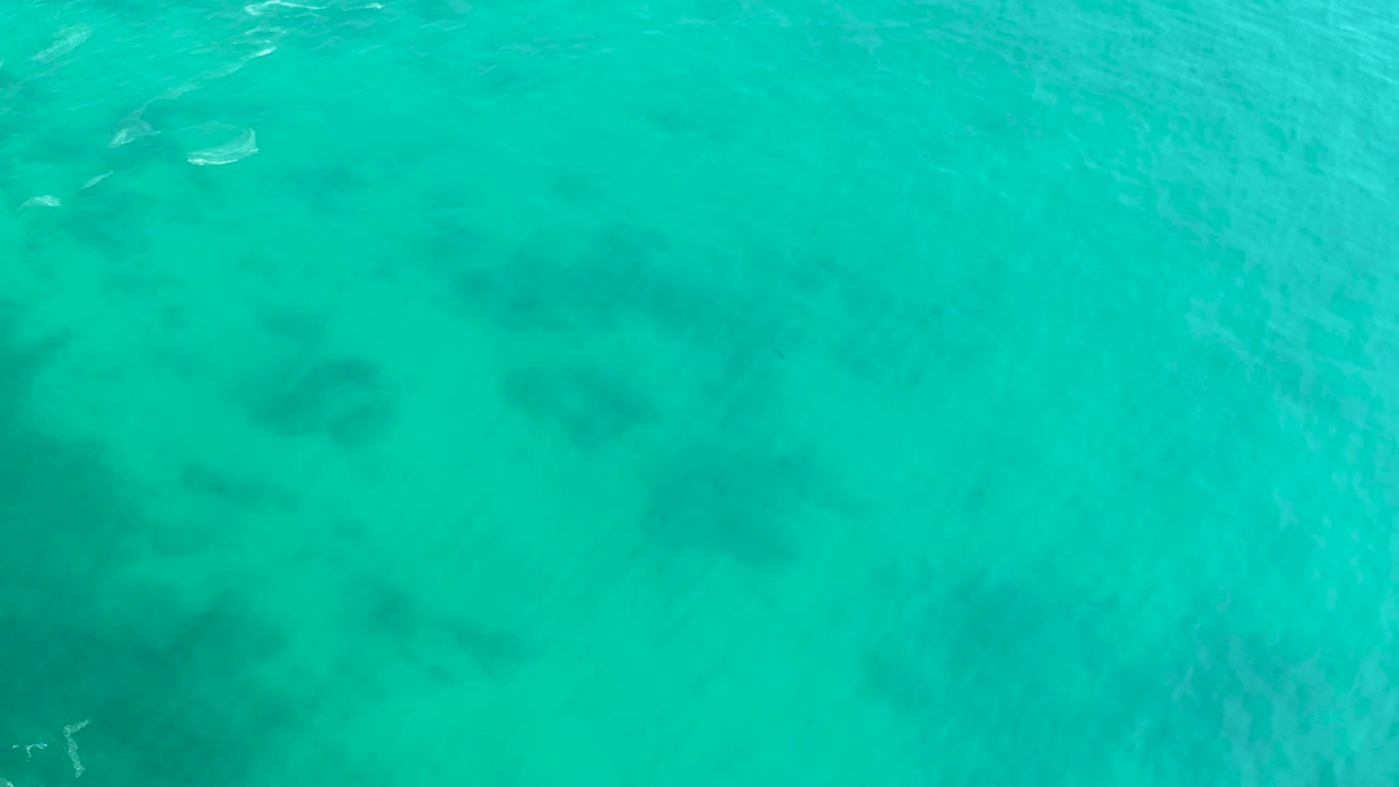 Turquoise ocean water with dark reef patches below the surface.