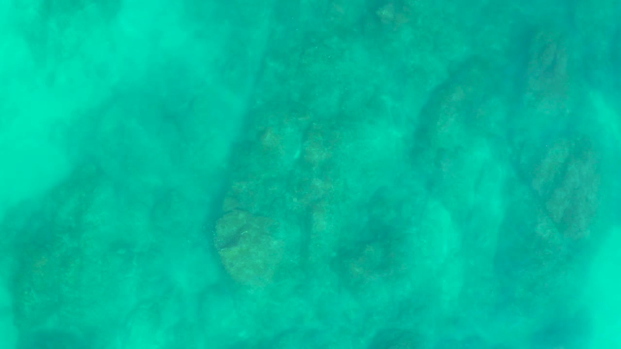 Turquoise shallow water over submerged rocks