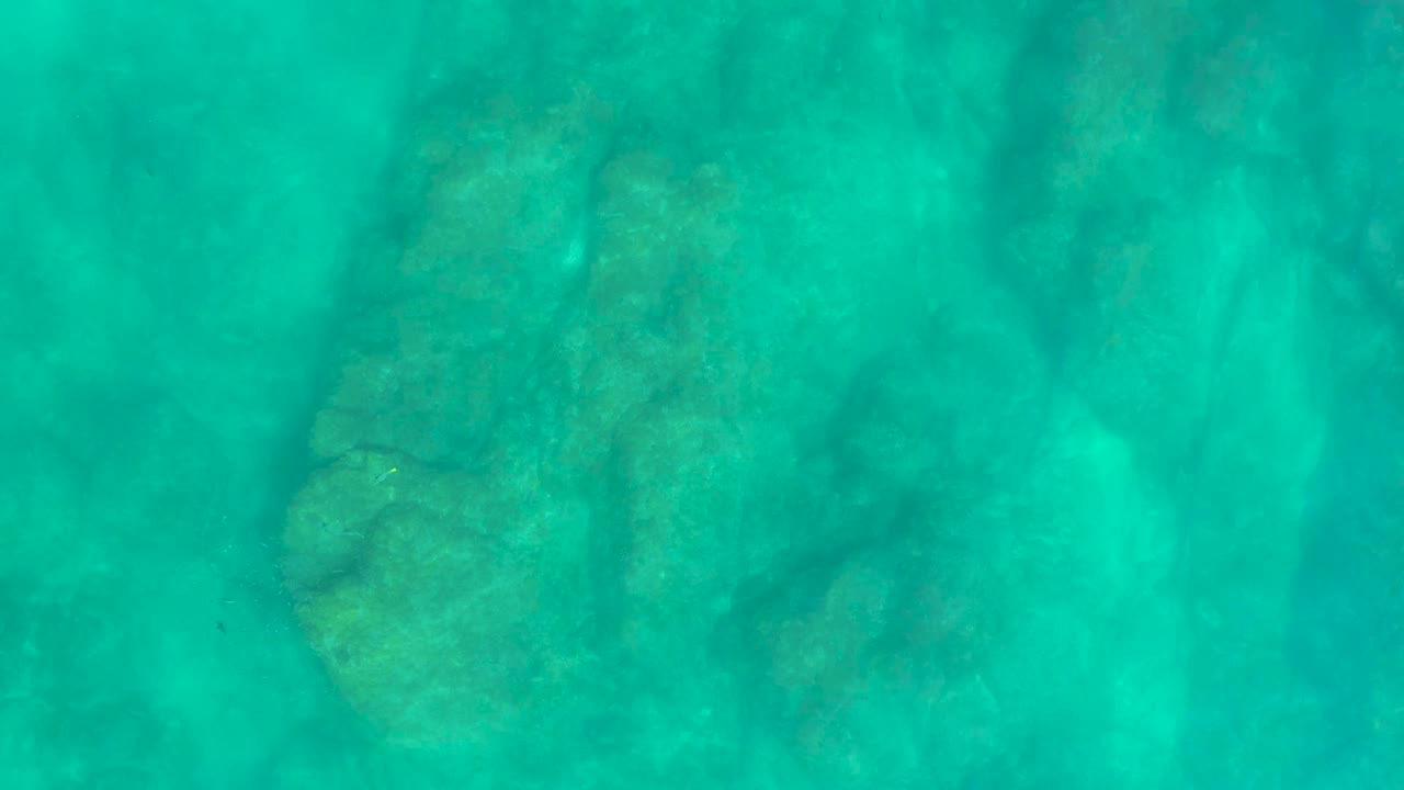 Second underwater frame at Shipwrecks Los Cabos with the seabed still visible through turquoise water and no visible people.