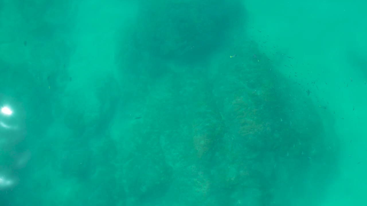 Turquoise underwater rocks with a bright light spot.