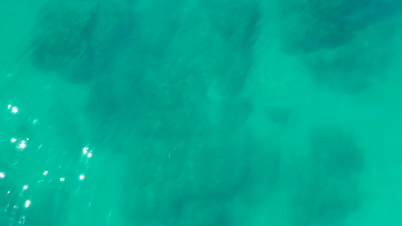 Turquoise water over dark coral formations