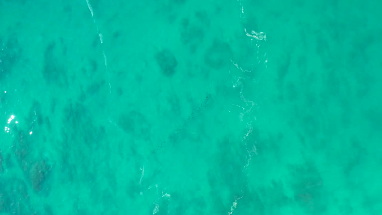 Overhead view of turquoise water at Shipwrecks Los Cabos with dark seabed patches under the surface and no visible people.
