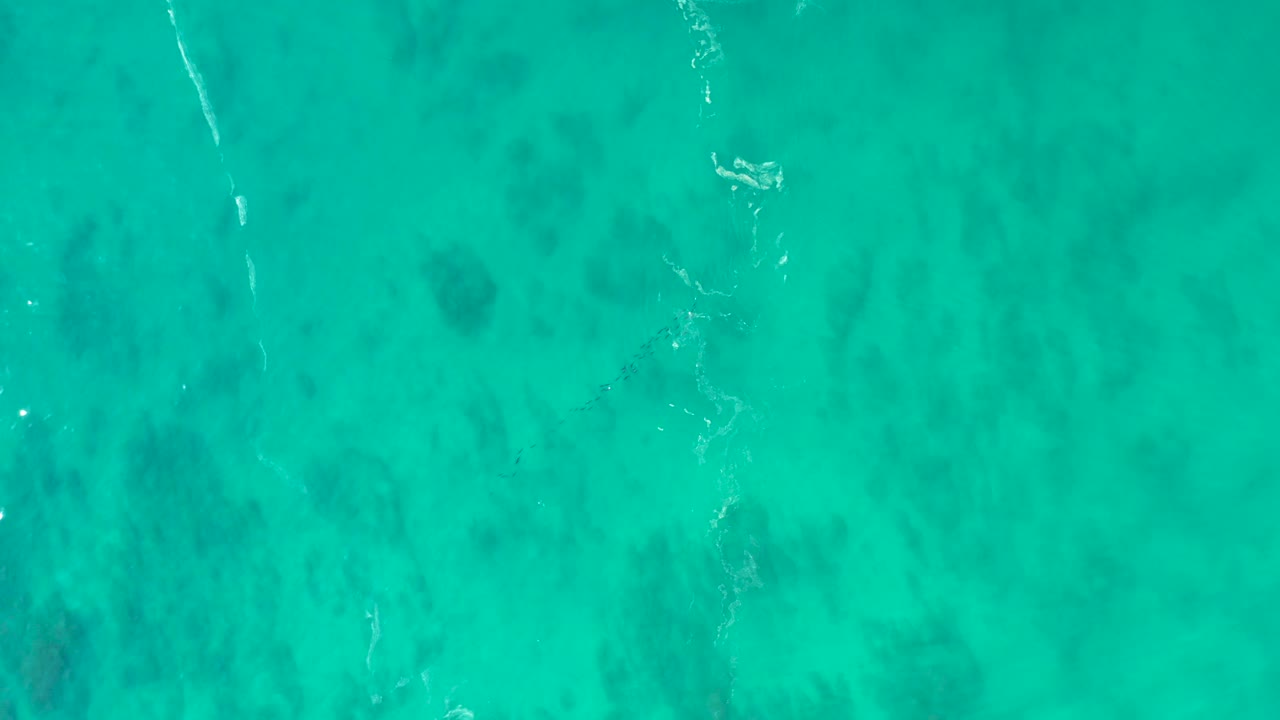 Shallow turquoise ocean at Shipwrecks Los Cabos, Mexico, includes a diagonal pale wave trace and mottled darker seabed areas with no visible people.