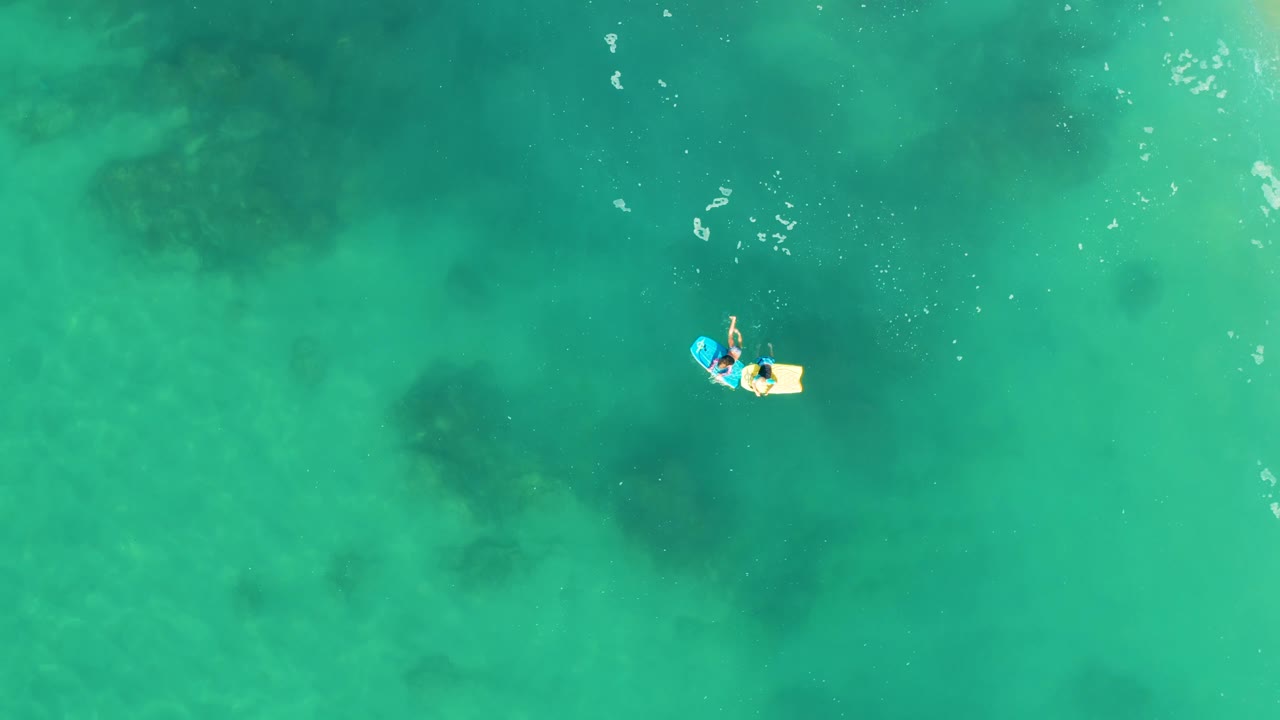 Person on a small float over clear green-blue ocean water.