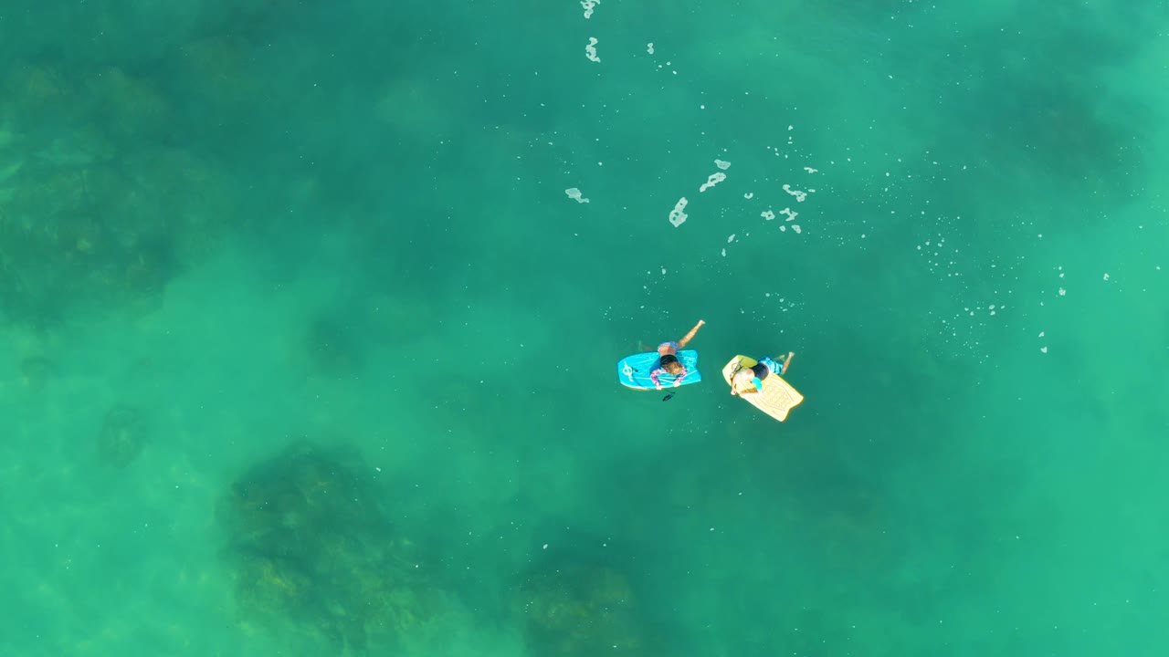 Two floating boards near the center of turquoise ocean water.