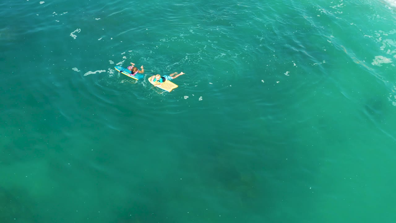 Two bodyboarders floating in open turquoise water.