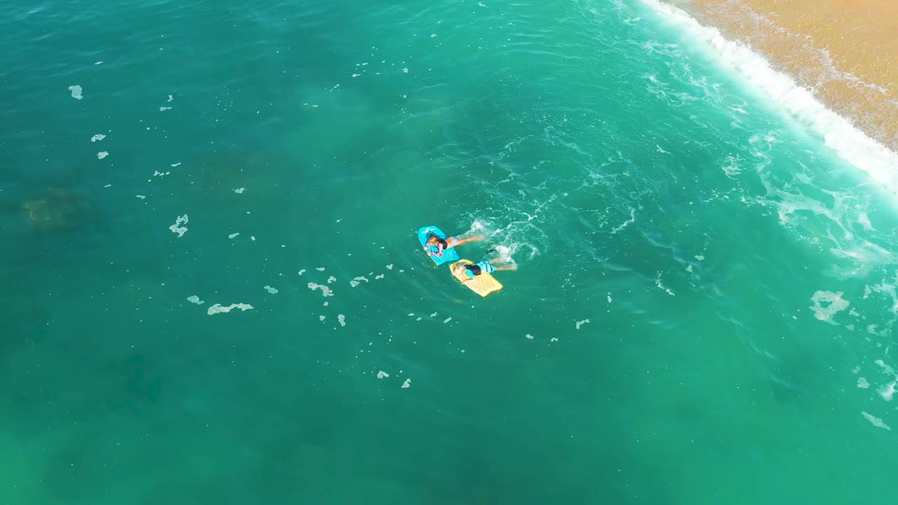 Person on a yellow bodyboard surrounded by clear green-blue ocean water and foam.