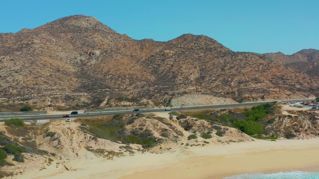 Wide coastal road with vehicles and arid hills