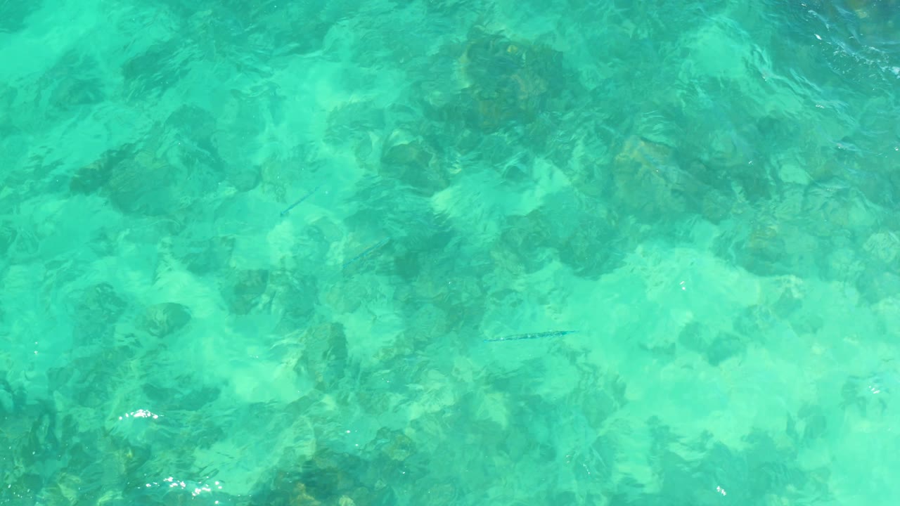 Turquoise water at Marquis Los Cabos, Mexico, with pale submerged rocks and slightly shifted surface ripples, no visible people.