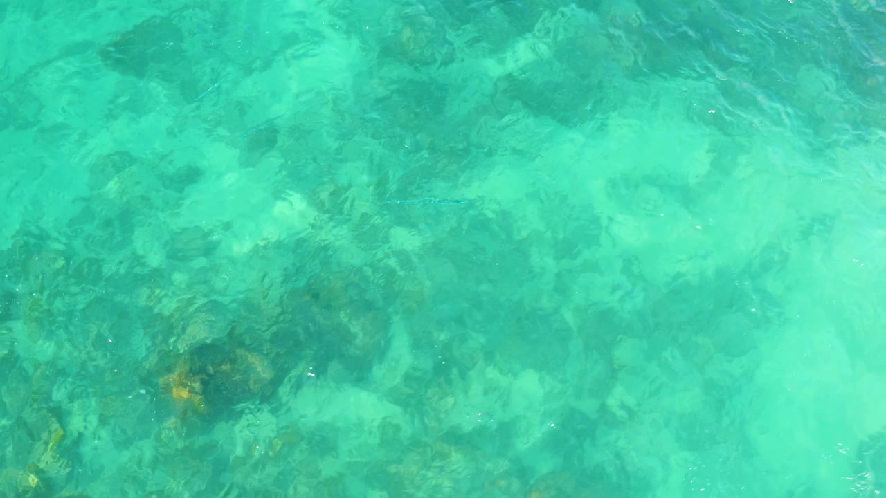 Turquoise shallow water at Marquis Los Cabos, Mexico, with submerged rocks visible through surface ripples and no visible people.