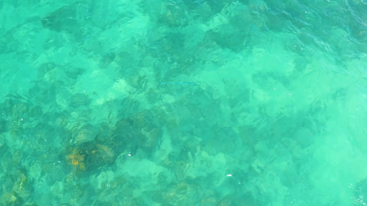 Clear turquoise water at Marquis Los Cabos, Mexico, with ripples shifting over darker rocks beneath the surface and no visible people.