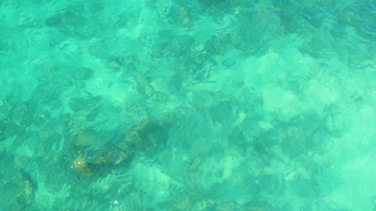 Rippling turquoise water over darker rocks