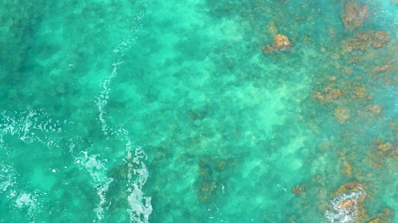 Bright aqua water with submerged rocks and foam