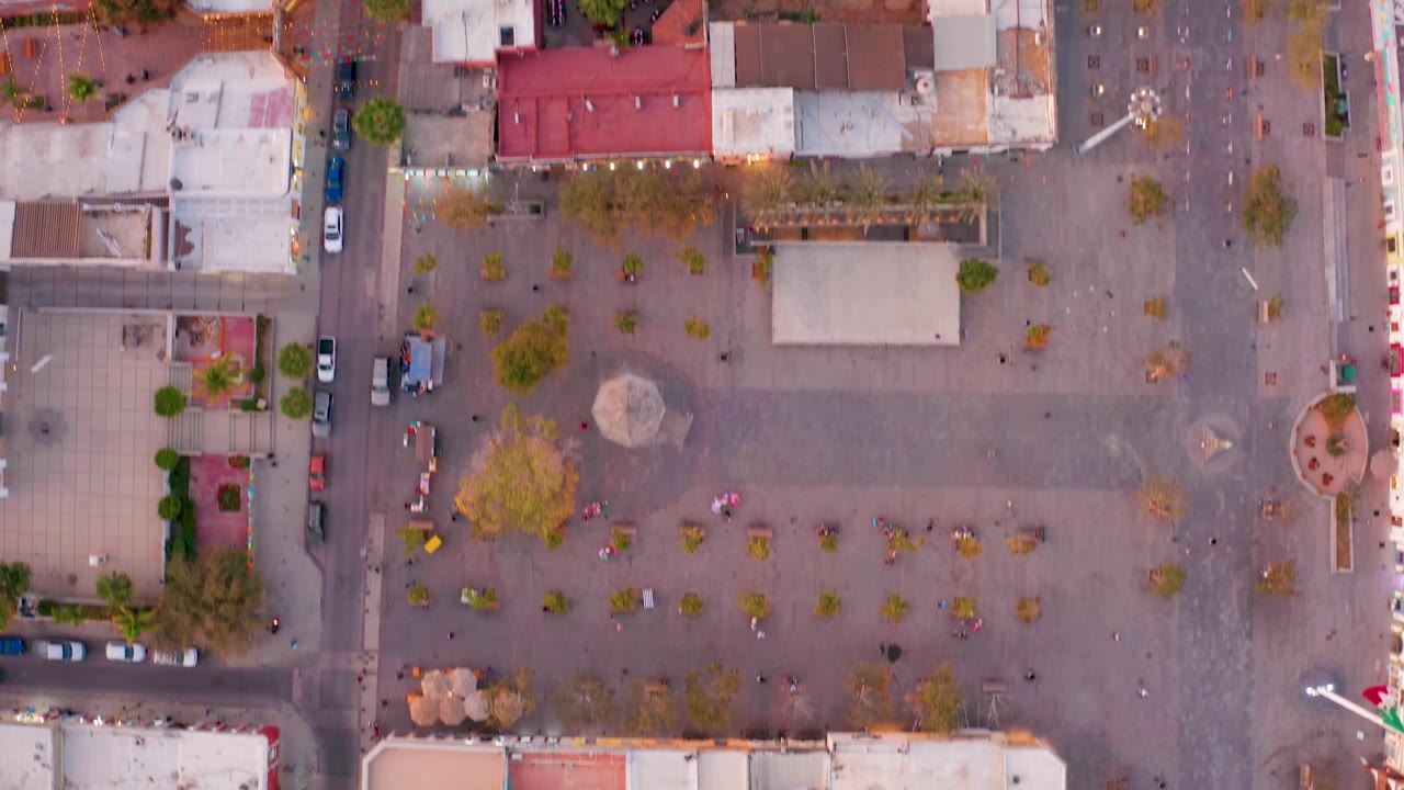 Overhead San Jose del Cabo frame with the plaza shifted across the view, showing patterned pavement, trees, flat rooftops, surrounding streets, and no discernible people.