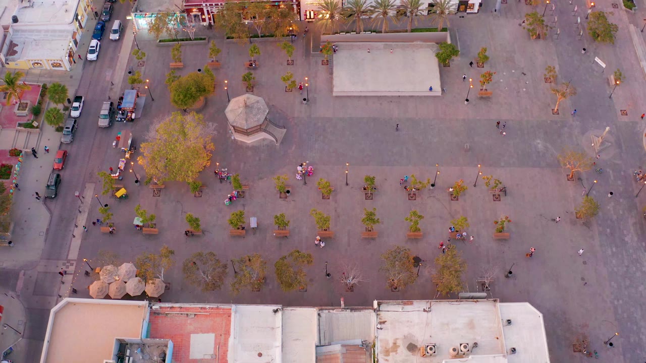 Aerial view of the same plaza with people walking near trees and the gazebo.