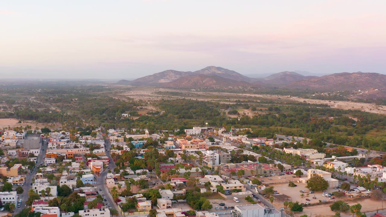 Town streets and rooftops below a green valley and mountain ridge.