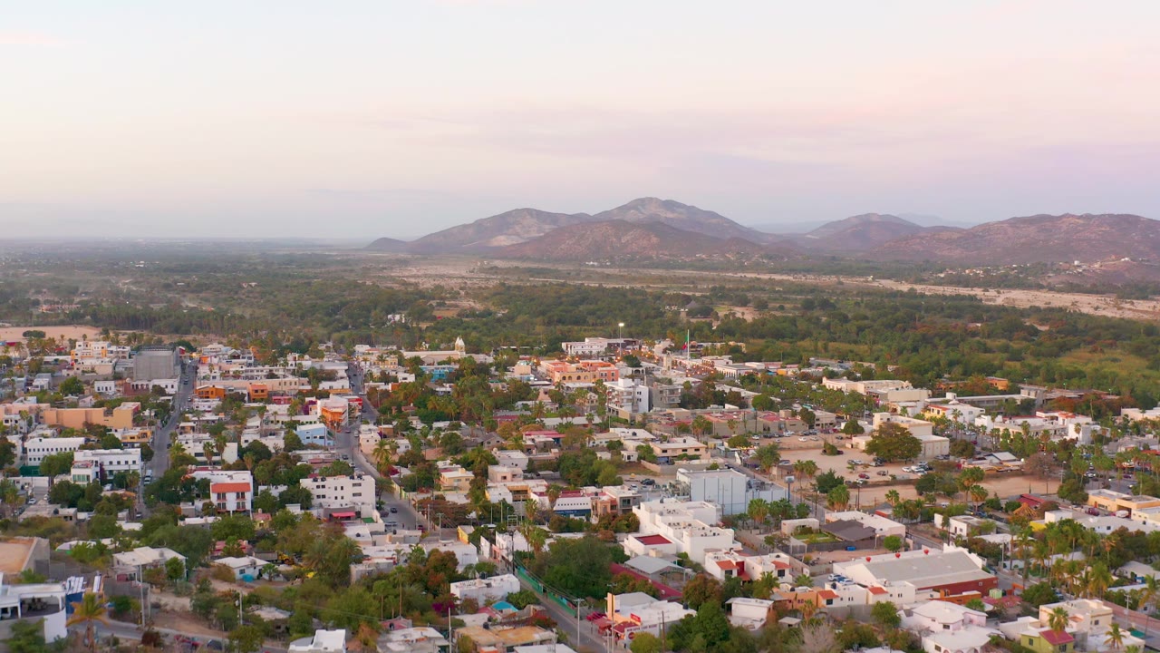 Residential blocks and tree cover seen from above with mountains in the background.