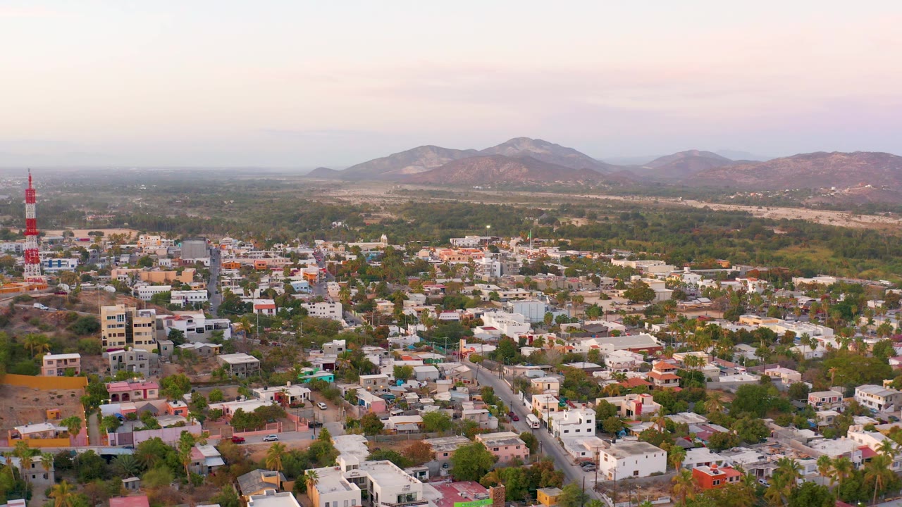 Residential buildings and roads below hazy mountains at sunset.