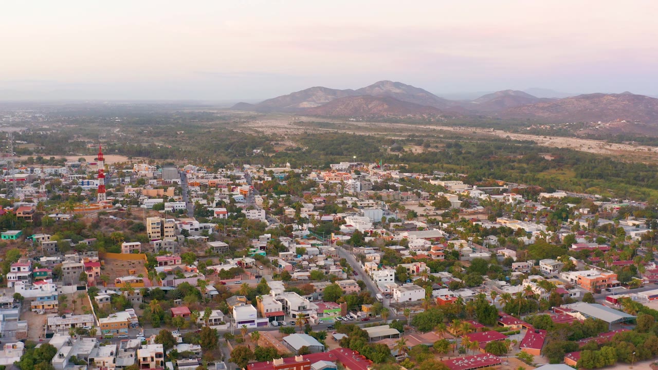 Aerial neighborhood view with tower, houses, and mountains.