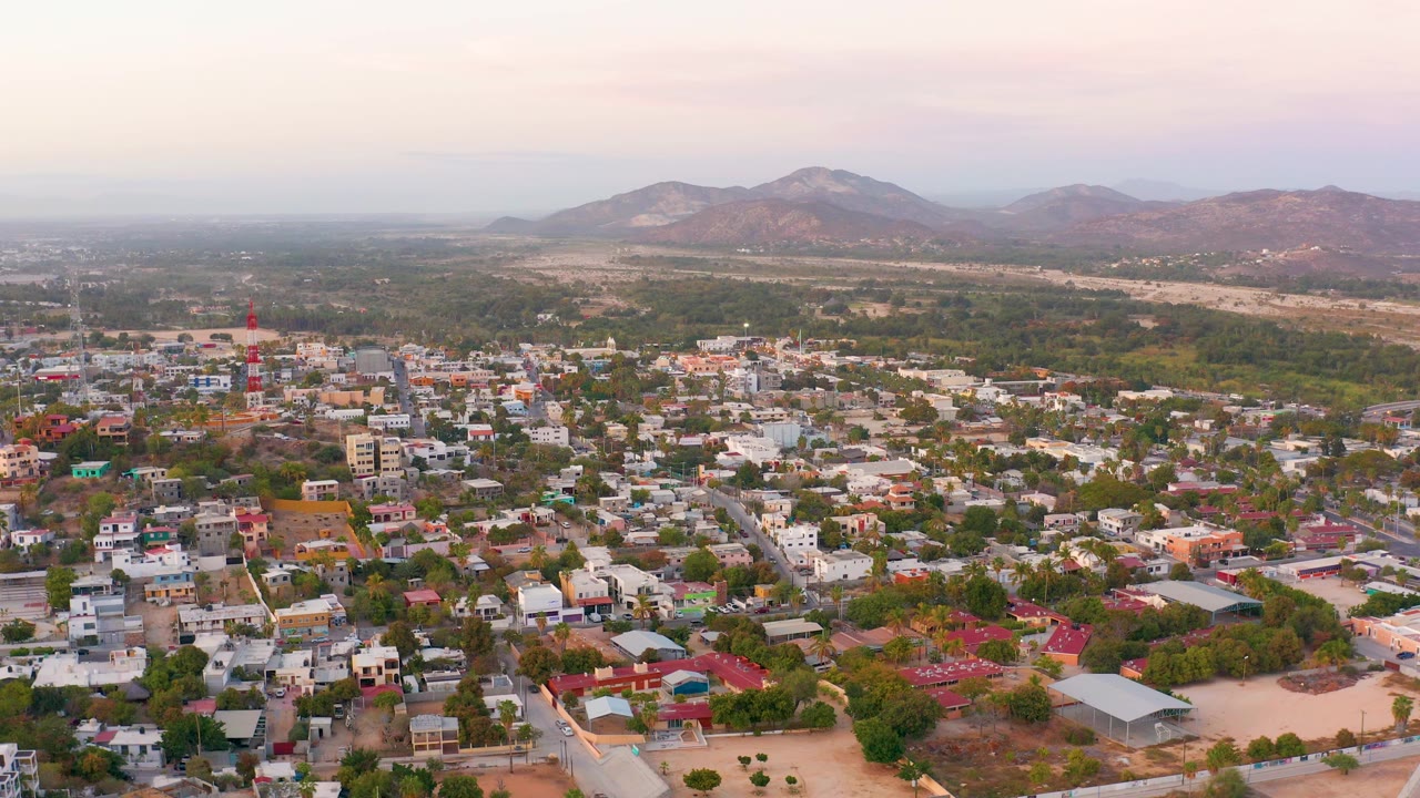 Aerial town panorama with a red tower and mountains.