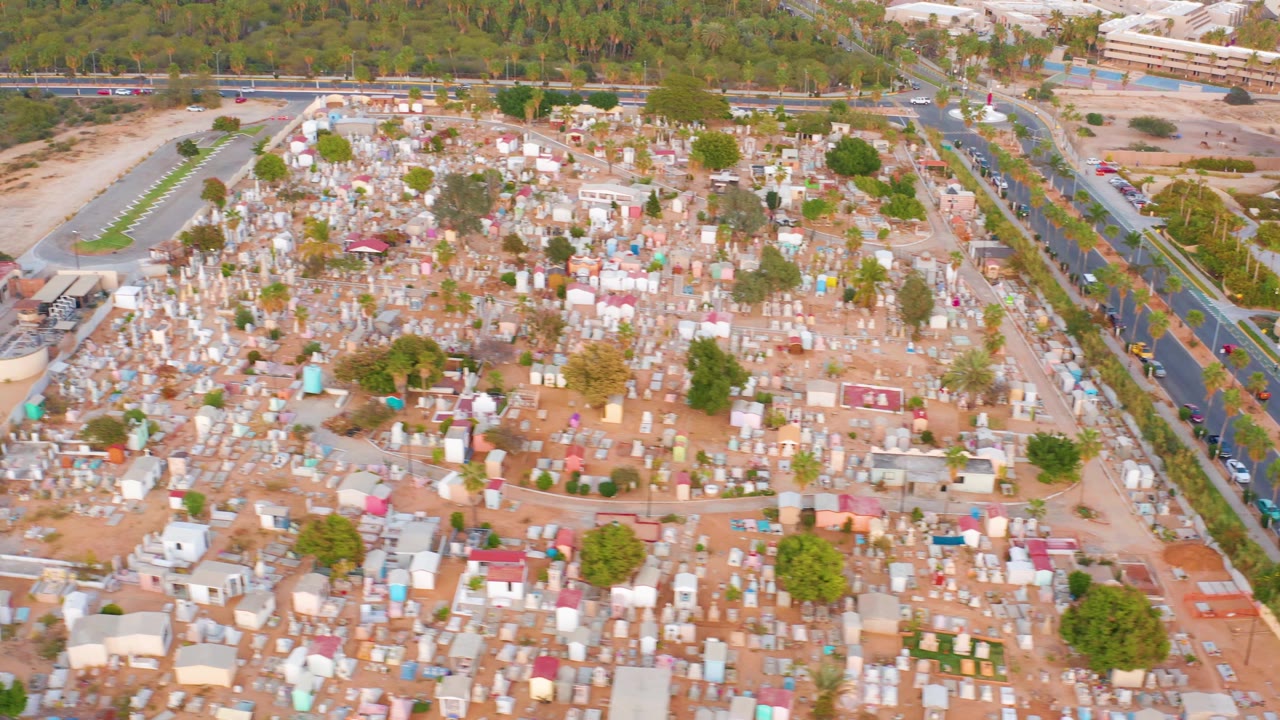 Aerial cemetery view with a curved building edge and road at the side.