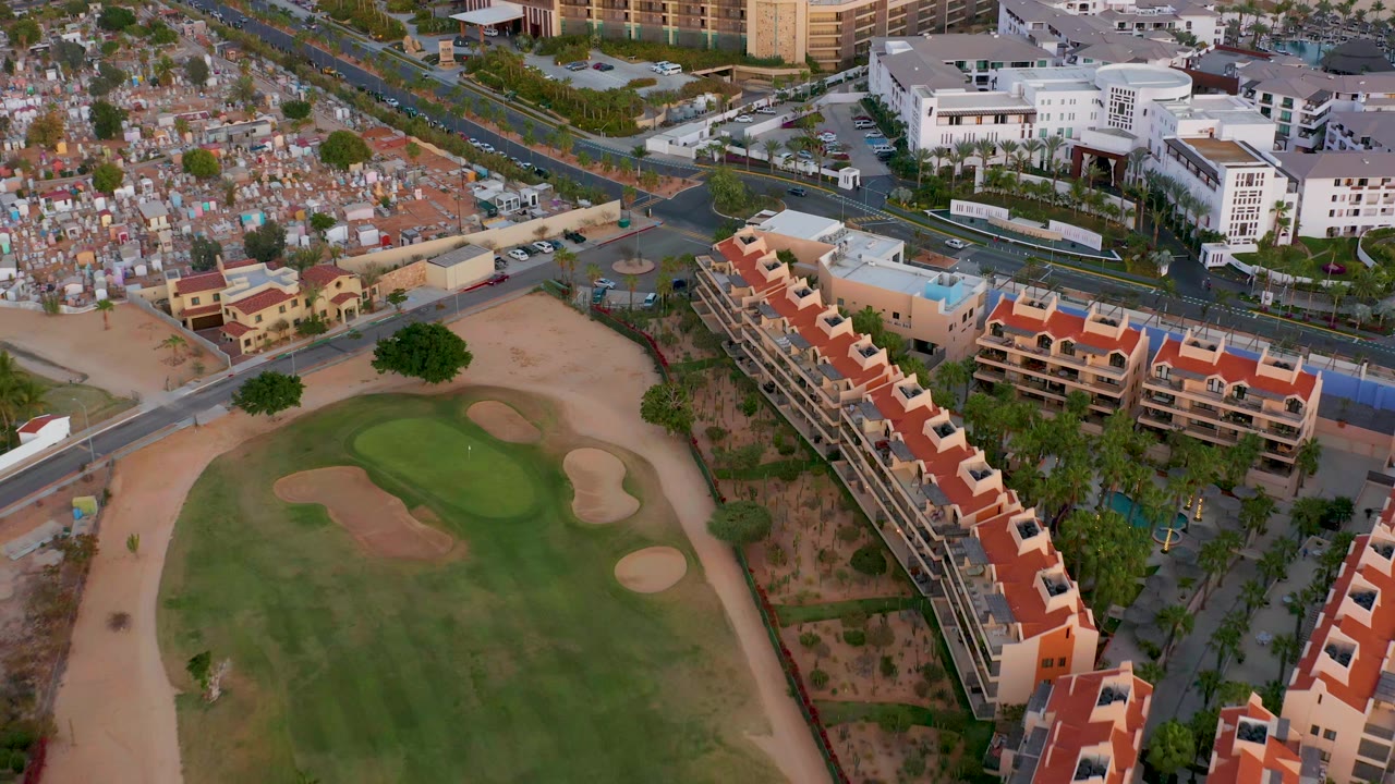 Golf green and sand traps bordered by apartments, streets, and low-rise buildings.