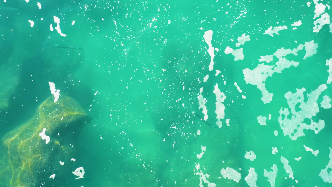 Turquoise water with a larger tan rock visible below the surface.
