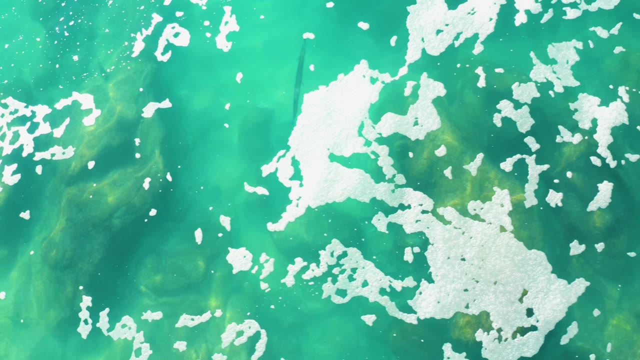 Turquoise ocean surface with white foam patches