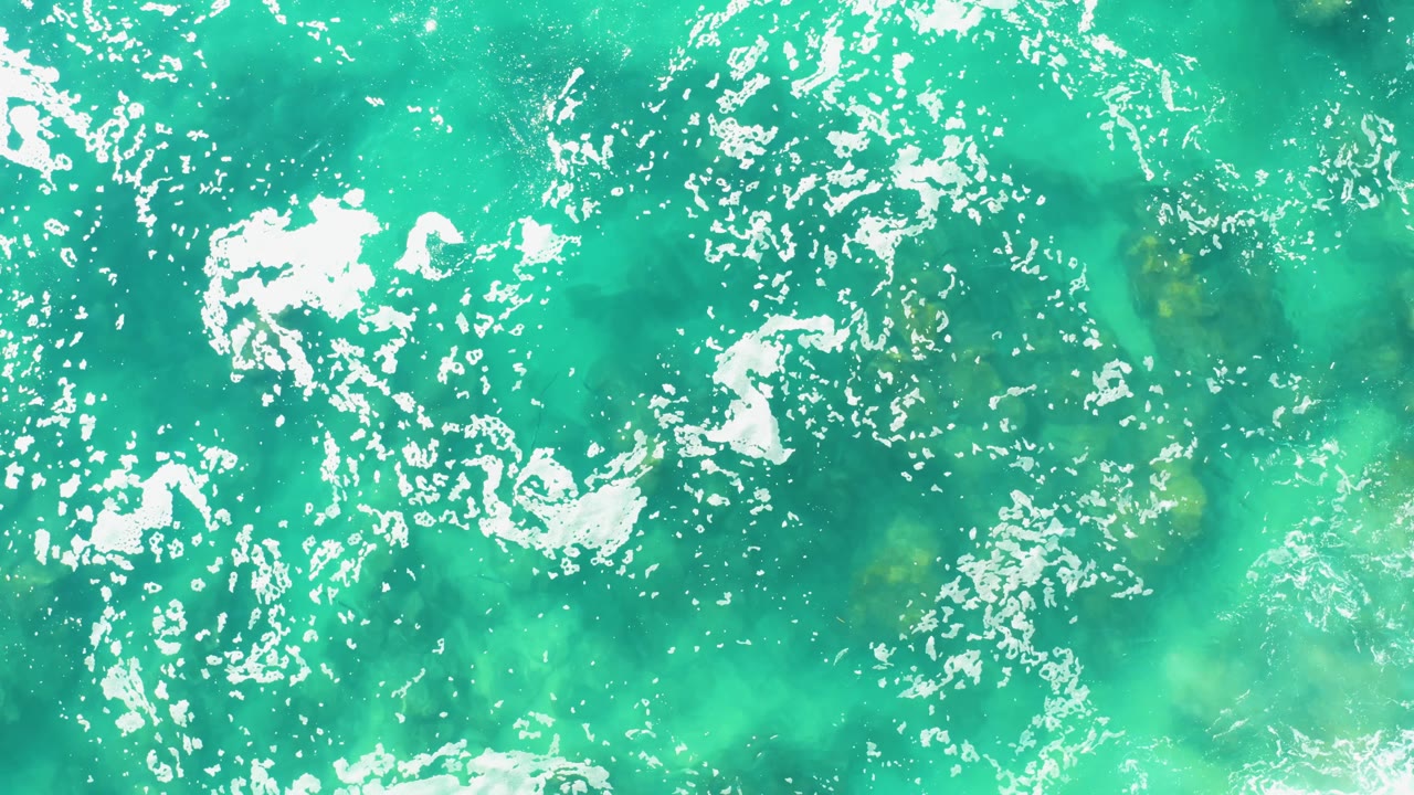 Turquoise shallow water with scattered foam and visible underwater color