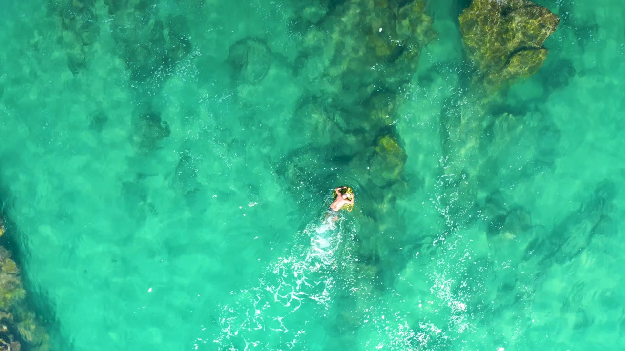 Swimmer leaving a white wake in turquoise water
