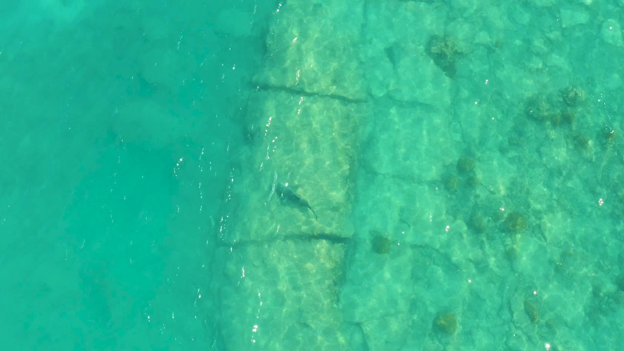 Turquoise water over a submerged stone structure.