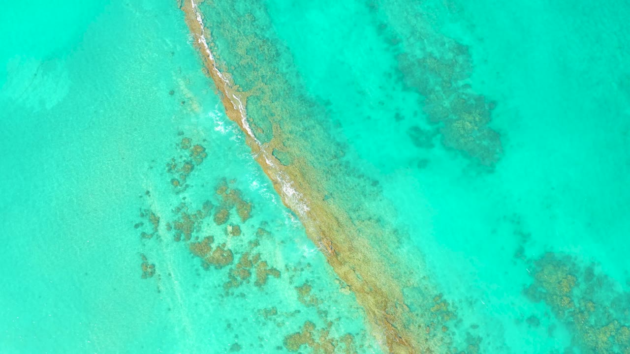 Cabo Pulmo overhead frame where a thin white surf line runs along the left side of the diagonal sandbar in bright turquoise water, with no visible people.