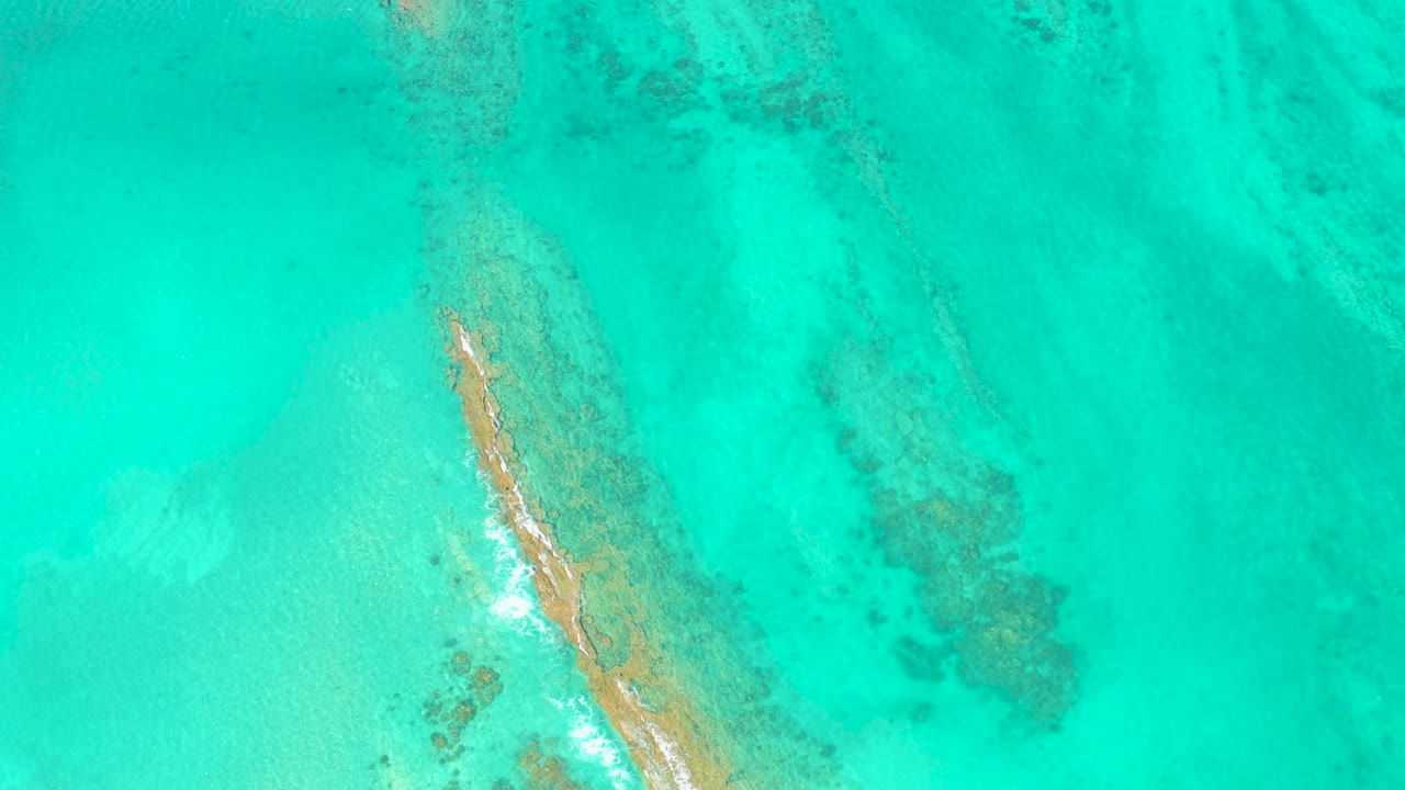 Overhead turquoise water with a narrow sandbar and reef patches.