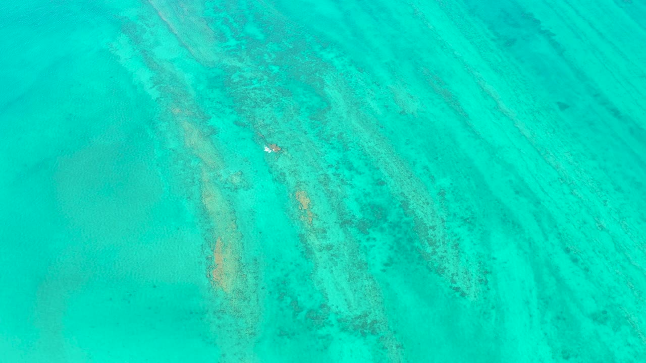 Clear turquoise ocean with diagonal seabed ridges.