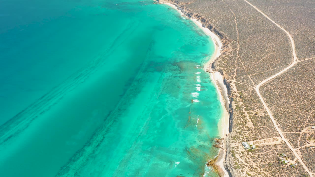 Coastal aerial view with darker underwater streaks and sandy edge