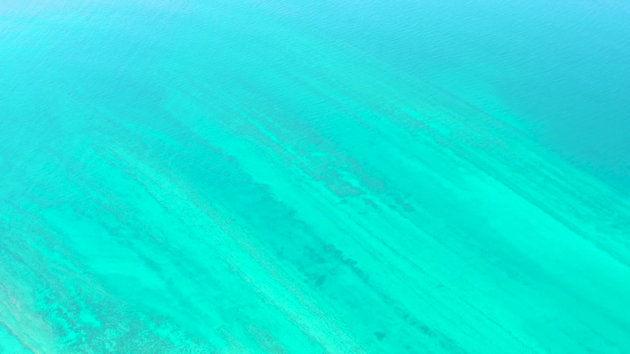 At three seconds, the frame shows clear turquoise water in Cabo Pulmo, with broad pale sand areas, faint darker underwater streaks, and no visible people.