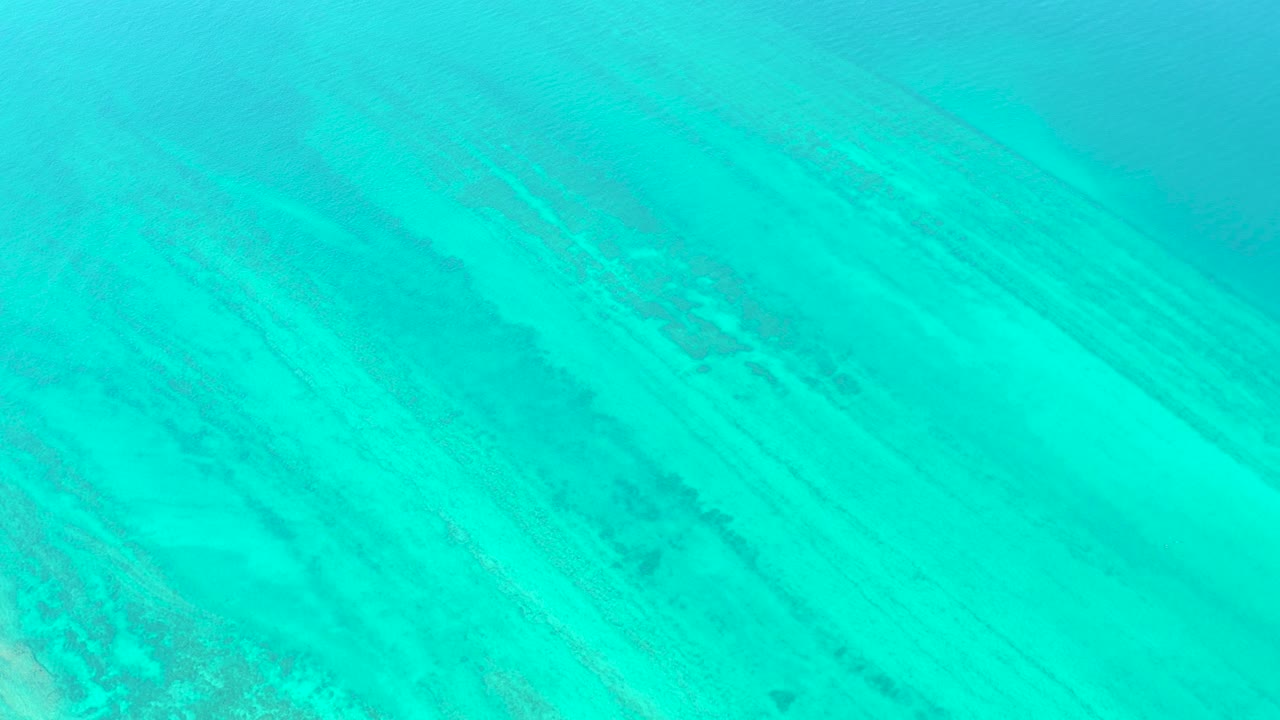 Opening frame of turquoise water over a pale sandy seabed in Cabo Pulmo, with faint darker underwater streaks and no visible people.