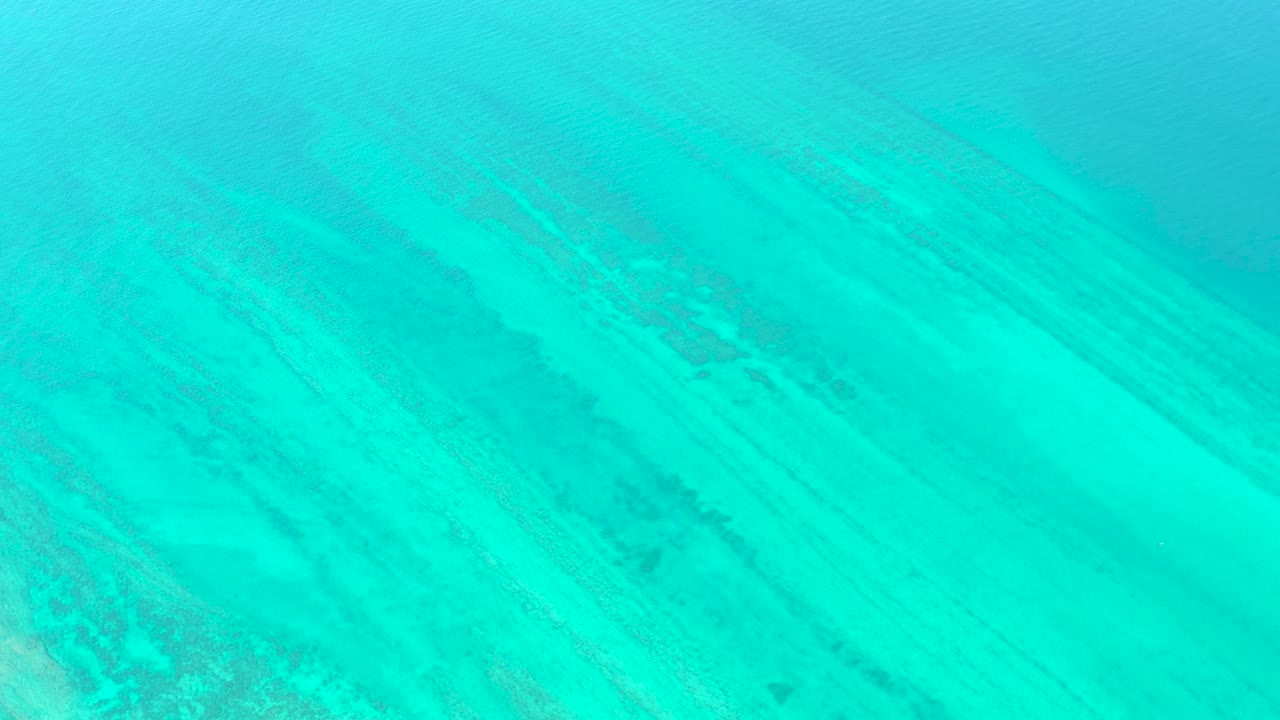 Turquoise ocean floor view with muted darker bands under the surface.