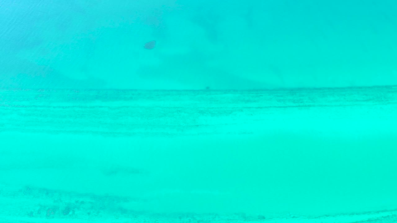 Turquoise shallow ocean water in Cabo Pulmo shows a faint sandy seabed through the surface, with no visible people.