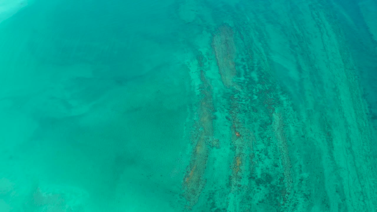 Clear turquoise water in Cabo Pulmo fills the frame, with a vertical band of darker reef texture and no visible people.