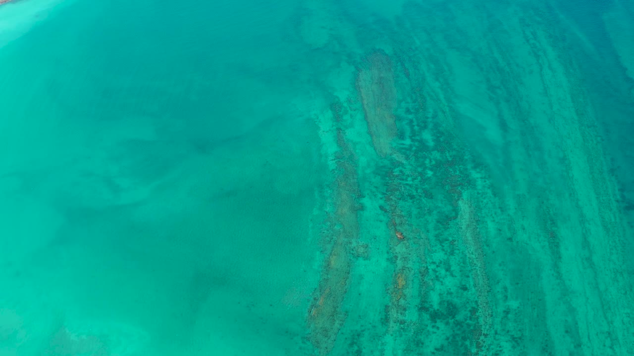 Aerial Cabo Pulmo water view with submerged reef streaks shifted toward the right side of frame and no visible people.