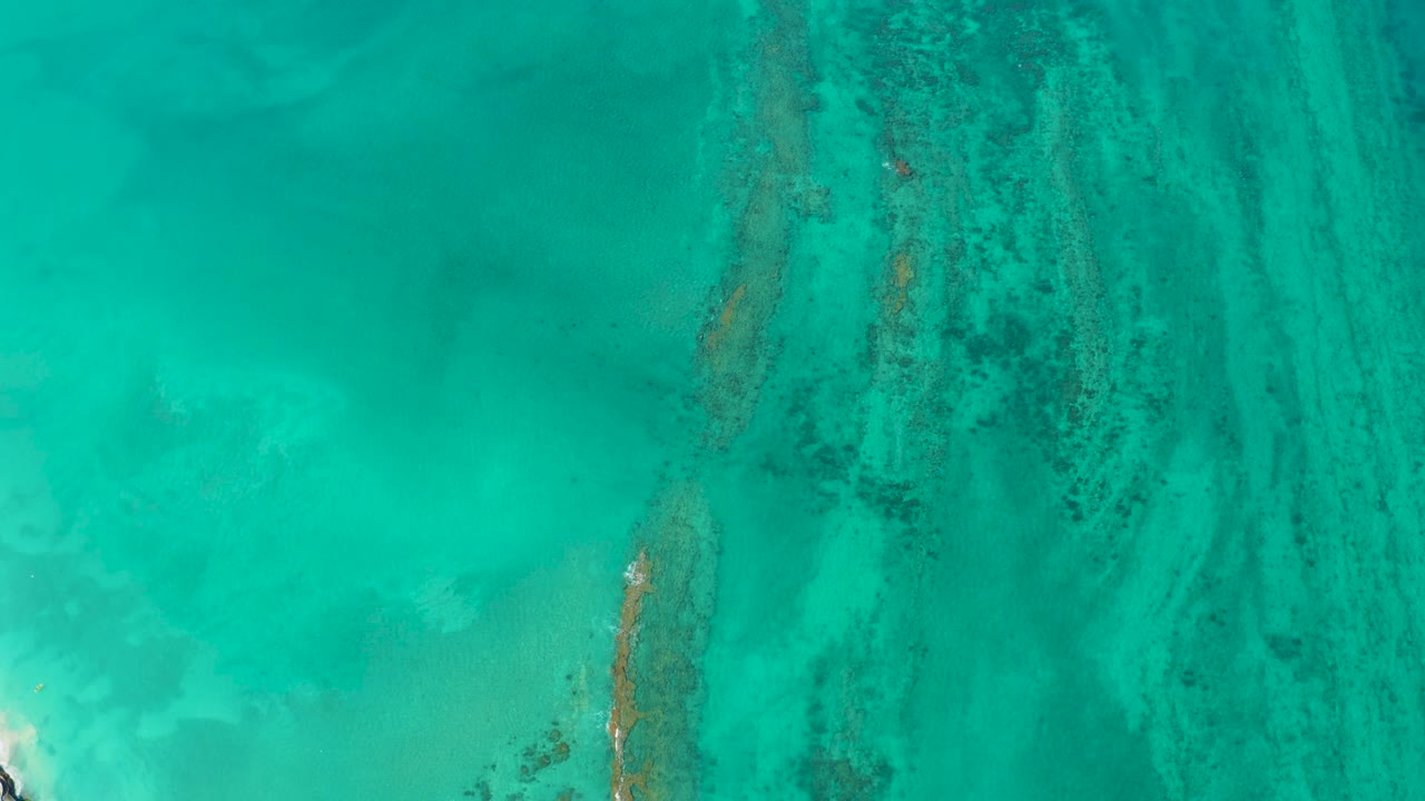 Turquoise water over dark reef streaks and pale sand