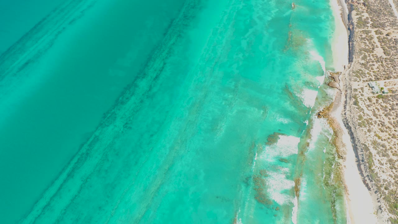 Clear green-blue water and beach seen from directly above