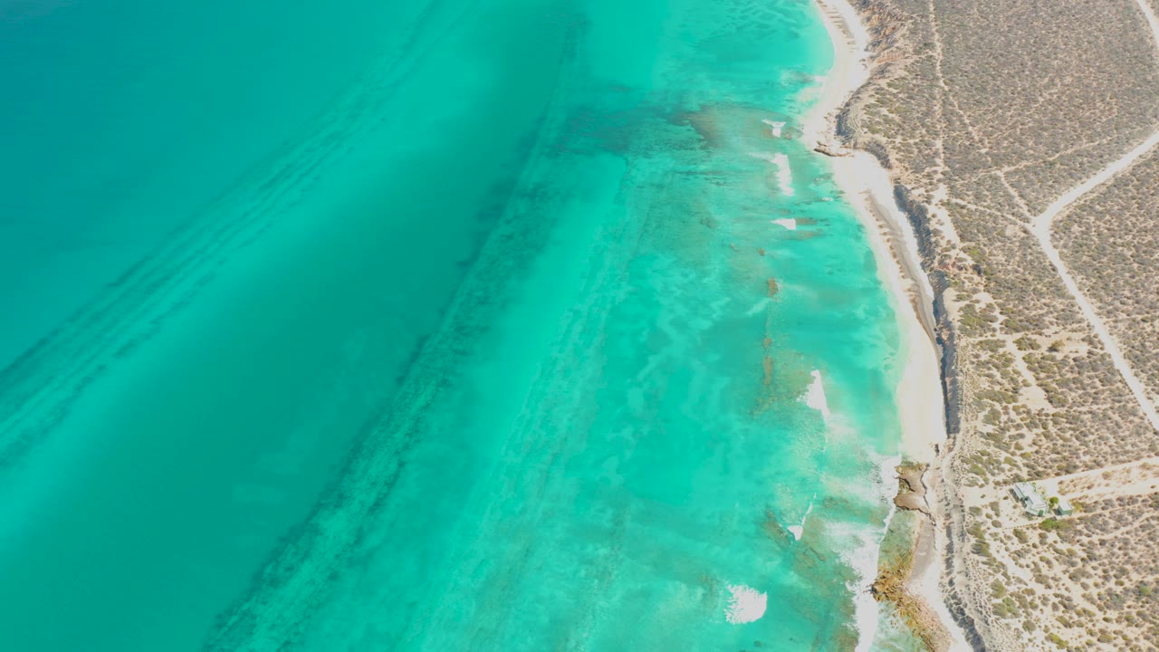 Overhead turquoise water beside a sandy coastal shore