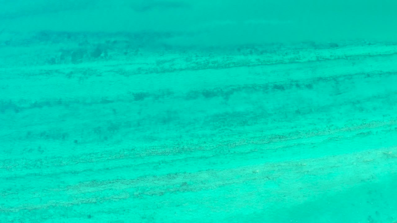 Turquoise ocean floor view with long darker streaks.