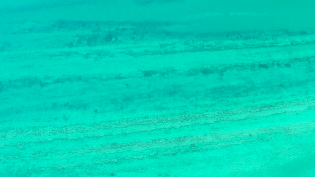 Turquoise shallow water in Cabo Pulmo shows soft ripple marks and layered seabed texture, with no visible people.