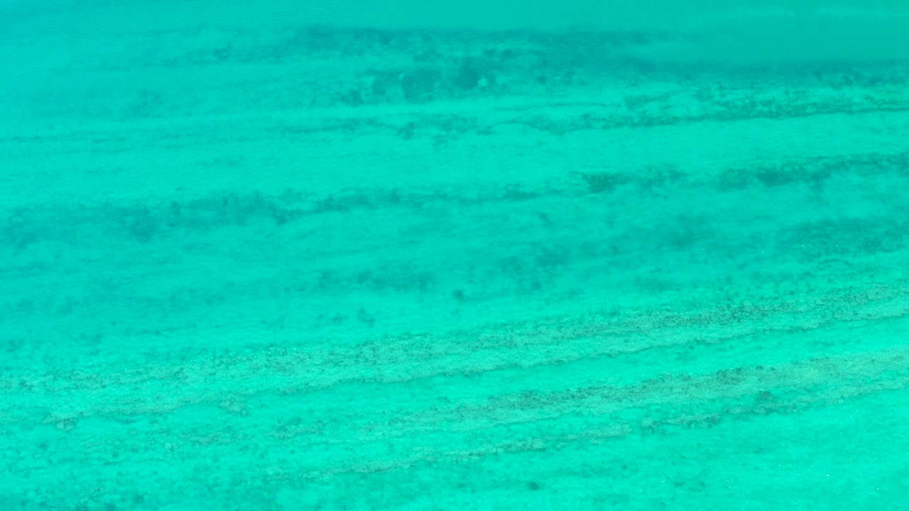 At two seconds, the frame shows bright turquoise Cabo Pulmo water over a sandy bottom with uneven darker lines and no visible people.