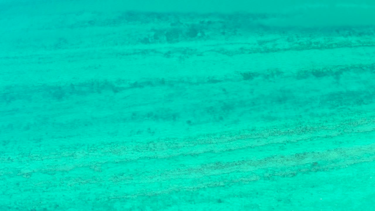 At three seconds, clear turquoise water covers a pale sandy Cabo Pulmo seabed with muted horizontal patches and no visible people.