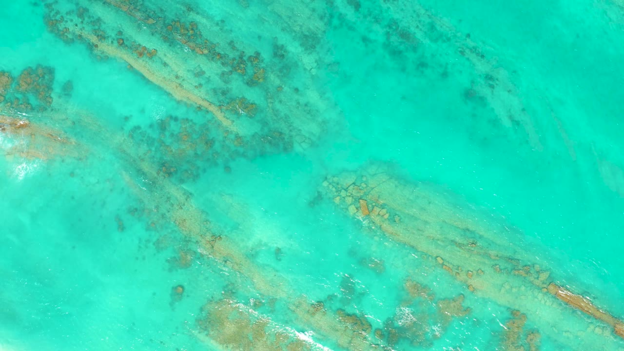 Calm turquoise water in Cabo Pulmo reveals submerged coral and rock formations across the frame, with no visible people or shoreline.